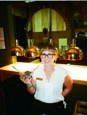A server holding a dessert at the bar