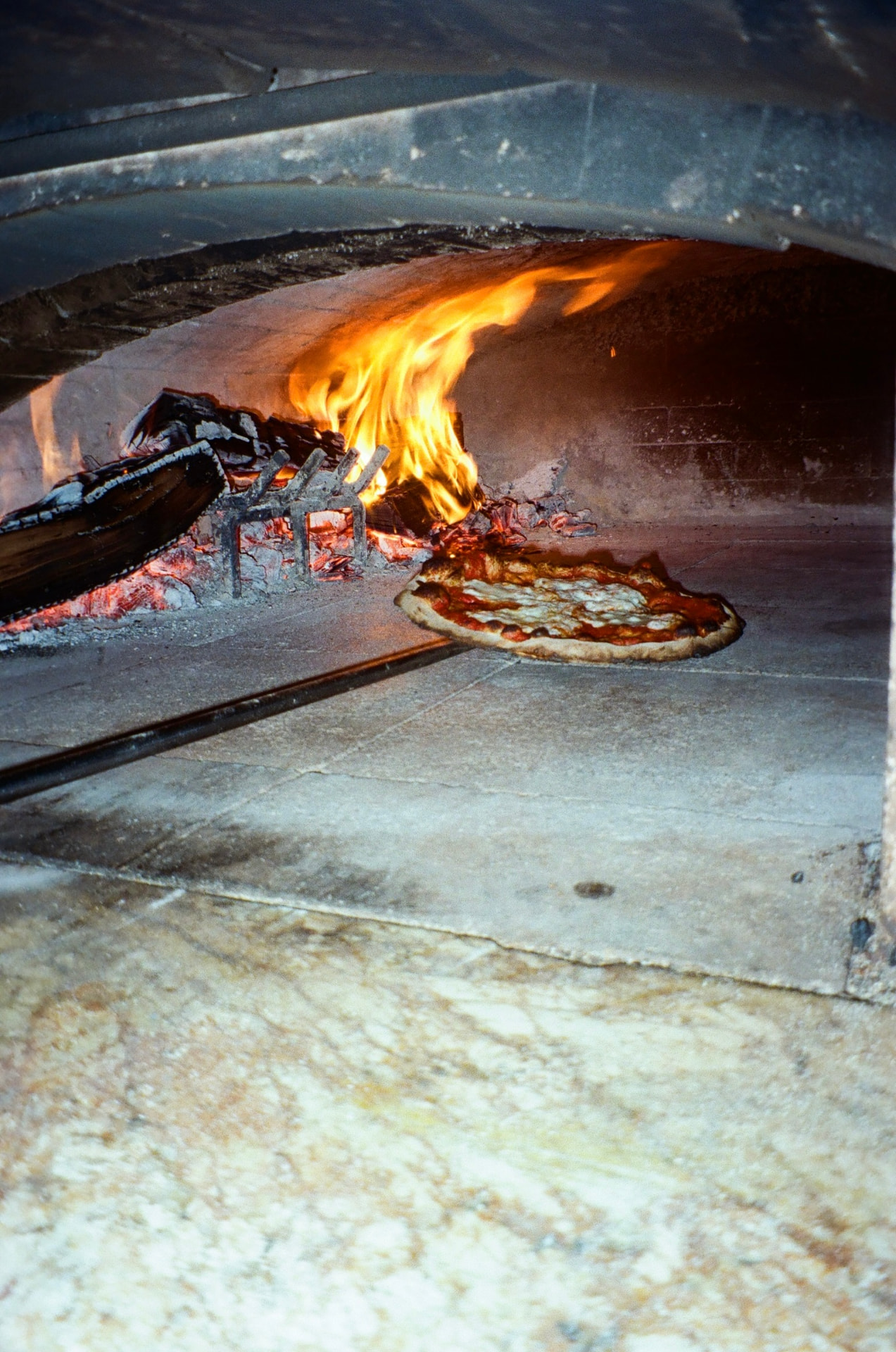 Neapolitan-style pizza baking beside the open flame of the wood-fired oven at Oak & Alchemy in Woodstock, IL